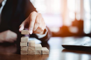 İş dünyasında plan ve strateji. Risk kavramı. İnsanın eli ahşap bir bloğu yığıp istifliyor..