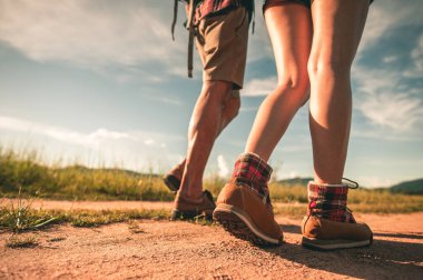 Sırt çantalı yürüyüşçüler orman yolunda yürürken dağ botları giyip ayakkabılara odaklanırlar..