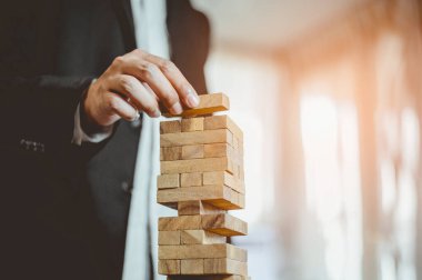 Modern ofisteki kuleye el çekmek ya da tahta bloğu yerleştirmek. Plan ve iş stratejisi. Arkaplan için bulanık.