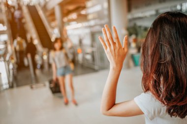 Asyalı kız abroaddan arkadaşlarını kucaklayacak. Havaalanı konsepti. Havaalanları kucaklaşması..