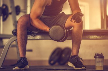 Vücut geliştirici, spor salonundaki halter ağırlıklarıyla çalışıyor. Halterle egzersiz yapıyor. Fitness kaslı vücut 