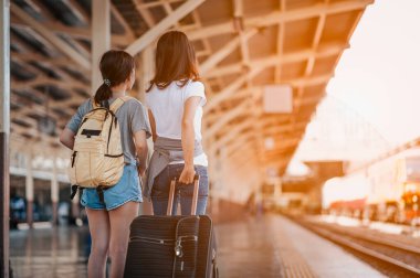 Tren istasyonunda bavulu çeken genç bir kadın. Taşıyıcıyı beklerken bavuluyla gezen adam. Uzayı kopyala.