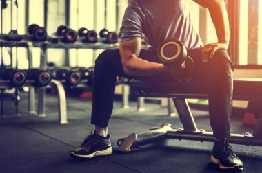 Vücut geliştirici, spor salonundaki halter ağırlıklarıyla çalışıyor. Halterle egzersiz yapıyor. Fitness kaslı vücut 