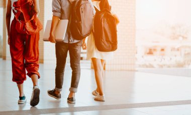 Bir grup öğrenci okula yürüyorlar. Öğrenciler çanta taşıyor ve okul ekipmanları var.