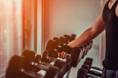 Jimnastik salonundaki birçok metal dambılı kapatın. Spor salonunda dambıllarla antrenman yapın. Dambılı eller.