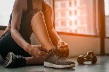 Spor salonunda ayakkabı bağı bağlayan bir kadın. Spor salonunda genç bir bayan antrenmana ara veriyor..