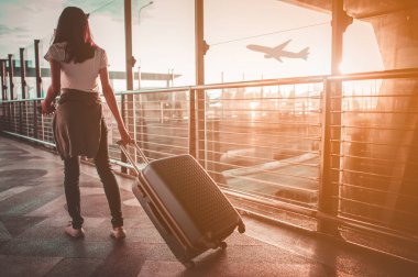 Havaalanı terminalinde bavulu çeken genç bir kadın. Boşluğu kopyala.