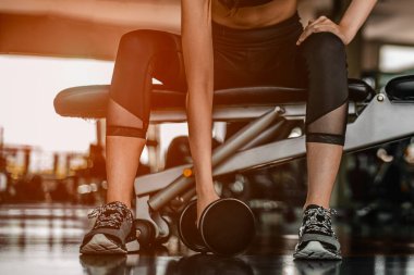 Spor salonunda dambıl ağırlıklarıyla çalışıyor. Spor salonunda spor yapan kadınlar, spor salonunun yanına yerleştirilmiş beyaz bir proteinle dambılları kaldırıyorlar. Spor salonunda spor yapıyorlar..