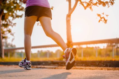 Aktif sağlıklı koşucu dışarıda koşuyor. Gün ışığında parkta koşan bir kadın.