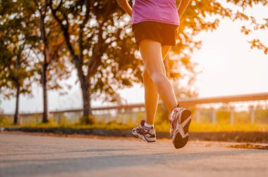 Aktif sağlıklı koşucu dışarıda koşuyor. Gün ışığında parkta koşan bir kadın.