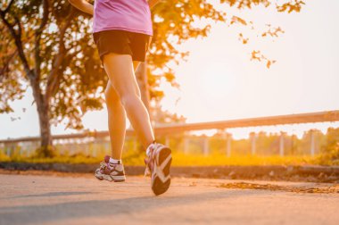 Aktif sağlıklı koşucu dışarıda koşuyor. Gün ışığında parkta koşan bir kadın.