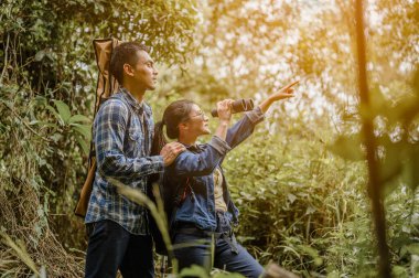 Asyalı çift, çam ormanlarında sırt çantasıyla gezmeyi ve uzun mesafe gözlükleriyle hayvanları izlemeyi seviyor..