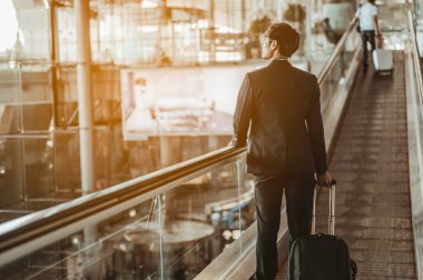 İş adamı havaalanından iş seyahatine bavuluyla giriş yapmak için terminal kapısına taşınıyor..