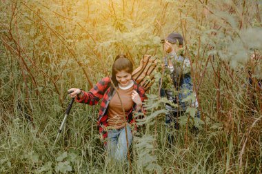 Ormanda yürüyüşçüler. Sonbahar ormanında yürüyüş yapan bir arkadaş. Kadın yürüyüşçü önünde mutlu bir şekilde gülümsüyor.
