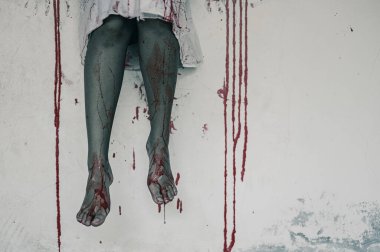 Kanlı bacaklı bir kadının korku sahnesi. Binada bacakları sallanan zombi kadın çığlık çığlığa karanlık ve cehennemden korkmak cadılar bayramı festivalinde şeytan kızdır.