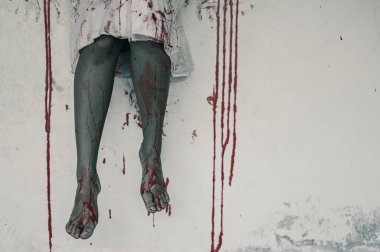 Kanlı bacaklı bir kadının korku sahnesi. Binada bacakları sallanan zombi kadın çığlık çığlığa karanlık ve cehennemden korkmak cadılar bayramı festivalinde şeytan kızdır.