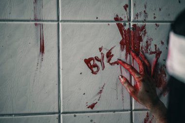 Korkunç kadın elinde kanla yardım isteyen bir mesaj yazmış. Cadılar Bayramı cinayet kavramı..