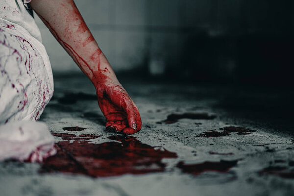 Девушка-зомби в крови, сидящая, испачканная кровью с обидой, пытает и просит помощи в заброшенном здании. Концепция убийства на Хэллоуин.