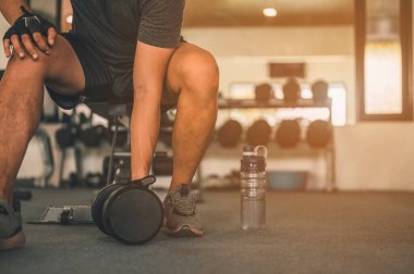 Vücut geliştirici, spor salonundaki halter ağırlıklarıyla çalışıyor. Halterle egzersiz yapıyor. Fitness kaslı vücut