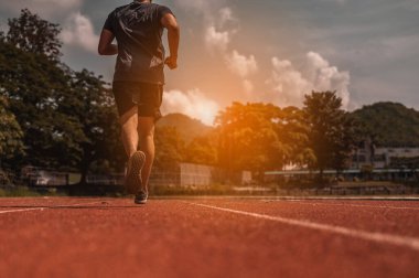 Yarış pistinde gün batımında spor antrenmanına hazır bir koşucu..