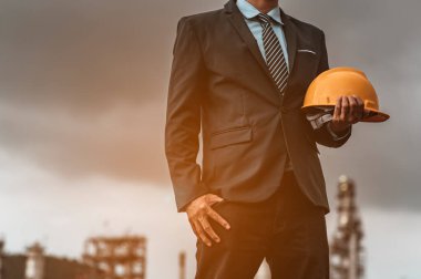 Erkek mühendis yakın plan bir güvenlik şapkası taşıyor ve gelecekte yeni binalar inşa etmenin yollarını ve fikirlerini düşünüyor. Mühendislik kavramları ve mimarisi