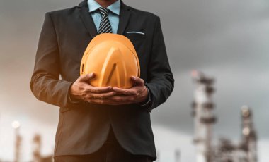 Erkek mühendis yakın plan bir güvenlik şapkası taşıyor ve gelecekte yeni binalar inşa etmenin yollarını ve fikirlerini düşünüyor. Mühendislik kavramları ve mimarisi