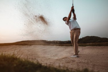 Yaşam tarzı, golf, aktivite, spor, golfçü konsepti. Bir adam golf sahasında güzel bir duruşla golfü süpürüp yazın günbatımında profesyonel olarak golf becerilerini geliştiriyor. Spor yaşam tarzı kavramı.