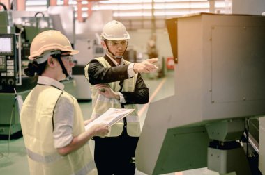 Mühendislik, mühendislik, endüstri, fabrika, teknoloji, iş konsepti. Kask takan erkek ve kadın sanayi mühendisleri, sanayi tesislerindeki yeni projeler üzerinde çalışmak ve konuşmak için dizüstü bilgisayar kullanıyorlar. Mutlu ve profesyonelce davrandılar. Mühendis