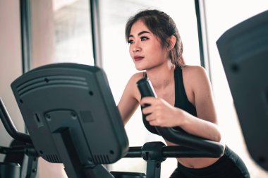 Spor, spor, spor, yaşam tarzı ve sağlıklı konsept. Gün batımında bisiklet üzerinde sağlıklı bir yaşam için spor salonunda egzersiz yapan önden kadın..