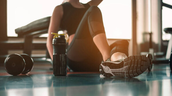 Healthy women are sitting and relaxing after exercising with whey protein after workouts at the indoor gym.