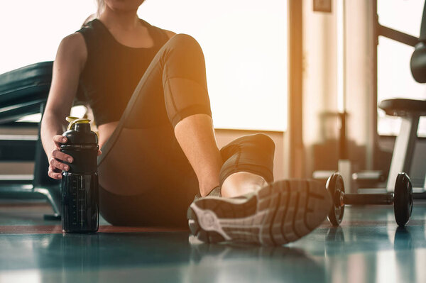 Healthy women are sitting and relaxing after exercising with whey protein after workouts at the indoor gym.