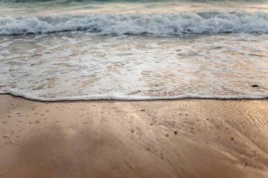 Deniz, sahil, kum, dalga, yaz, arka plan konsepti. Yazın gün batımında kumlu bir sahilde beyaz dalgalar. Arkaplan deniz konsepti.