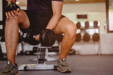 Fitness, koşu, egzersiz, yaşam tarzı ve sağlıklı konsept. Genç erkekler spor giyer, günbatımında spor salonunda egzersiz yapmak için halterleri hazırlayın..