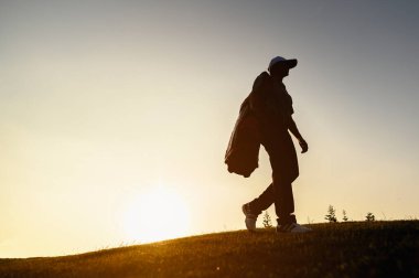 Yaşam tarzı, golf, aktivite, spor, golfçü konsepti Bir adam golf sahasında golf yeteneklerini geliştirmek için golf çantası taşır. Spor yaşam tarzı kavramı.