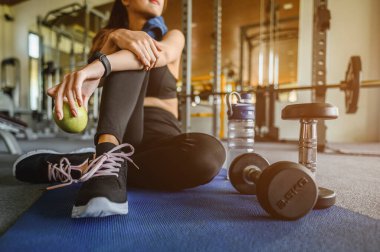 Spor, spor, spor, yaşam tarzı ve sağlıklı konsept. Gün batımında spor salonunda antrenmandan sonra elinde elma tutan bir kadın..