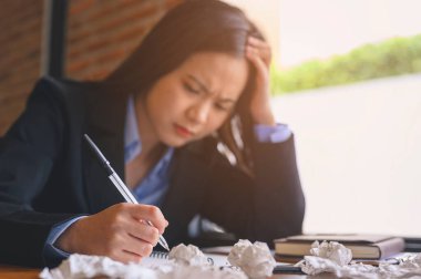 İş kadını, iş, iş, teknoloji, birden fazla iş, yaşam tarzı konsepti. İş kadını yorgun, ofis masasında dizüstü bilgisayar ve buruşuk kağıtlarla oturuyor. Kadınlar konsantre olamıyor ve işe gidemiyor..
