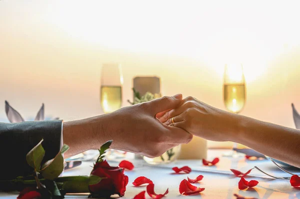 Gün batımında restoranda el ele tutuşan çift yemek yiyor. Sevgililer Günü, Çift, Balayı, Akşam Yemeği, Şarap, Romantik Konsept. 