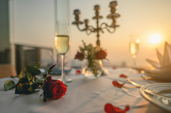 Roses on the table for the lover's Valentine dinner With wine glasses and candlesticks. Sunset views on tall buildings. Valentine's, Couple, Honeymoon, Dinner, Wine, Romantic concept. 
