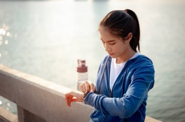 Genç kadın, şehirde sabah antrenmanından sonra nabzını akıllı bir şekilde kontrol ediyor. Başkentte sağlıklı yaşayan bir şehir. Egzersiz, fitness, koşu, koşu, yaşam tarzı, sağlıklı konsept.