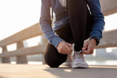 Genç kadınlar sabahları şehirde spor yaparken ayakkabılarını bağlamak için ellerini kullanıyorlar. Başkentte sağlıklı yaşayan bir şehir. Egzersiz, fitness, koşu, koşu, yaşam tarzı, sağlıklı konsept