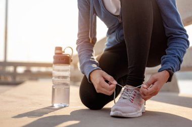 Genç kadınlar sabahları şehirde spor yaparken ayakkabılarını bağlamak için ellerini kullanıyorlar. Başkentte sağlıklı yaşayan bir şehir. Egzersiz, fitness, koşu, koşu, yaşam tarzı, sağlıklı konsept