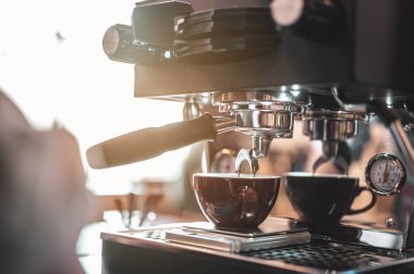 Yakın plan kahve makinesi, kahve barmeninin akşam güneşinde koyu beyaz bardakla kahve çıkarmasını sağlıyor. kahve, çıkartma, derin, makine, yapım, barista konsepti. 