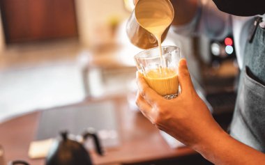 Kahve barmeninin kahve fincanına buğulanmış süt doldurup güzel latte sanatları yaptığı yakın plan çekimler. kahve, çıkartma, derin, fincan, sanat, barista konsepti. 