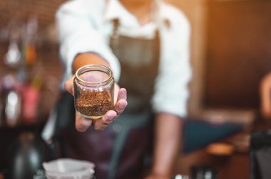 Kahveci adamın elinde öğütülmüş bir kahve çekirdeği var. Erkek elleri masaya bir fincan kahve koyuyor. Kahve, barista, çıkarma, servis, kafe, yaşam tarzı konsepti..