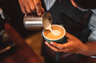 Kahve barmeninin kahve fincanına buğulanmış süt doldurup güzel latte sanatları yaptığı yakın plan çekimler. kahve, çıkartma, derin, fincan, sanat, barista konsepti. 