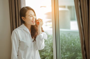 Genç bayan Asya sabah dinlenmiş olarak uyanır ve dinlenir kahve, mısır gevreği, ekmek ve elmayı tatilde evde kahvaltı için yer. Asya, Asya, rahatla, kahvaltı, ferahlatıcı, yaşam tarzı konsepti.