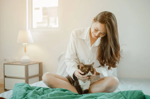 Young woman asia wake up refreshed in the morning playing with cats at bed happily on holiday. Asian, asia, relax, happiness, refresh, lifestyle concept.