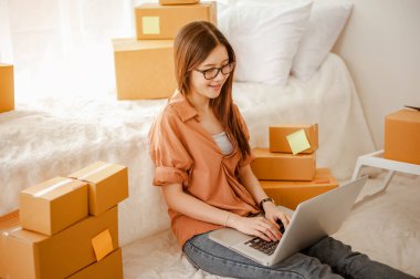 Genç Asyalı kadın müşterilerle çevrimiçi ürün satmak ve müşterilere teslimat yapmak için konuşuyor. İş sahibi, KOBİ, taşımacılık, evden (WFH), serbest, başlangıç konsepti.