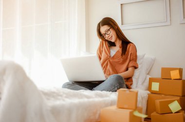 Genç Asyalı kadın müşterilerle çevrimiçi ürün satmak ve müşterilere teslimat yapmak için konuşuyor. İş sahibi, KOBİ, taşımacılık, evden (WFH), serbest, başlangıç konsepti.