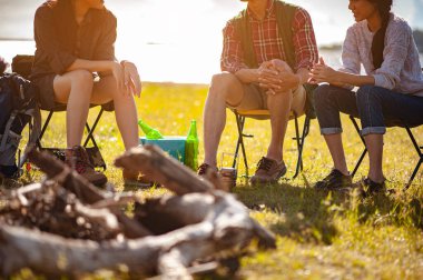 Asyalı dağcı takımı sonbahar sezonunda orman yolunda kurulmuş bir çadırdan sonra oturup bir içkinin tadını çıkarıyorlar. Yürüyüş, yürüyüş, takım, orman, kamp, aktivite konsepti.